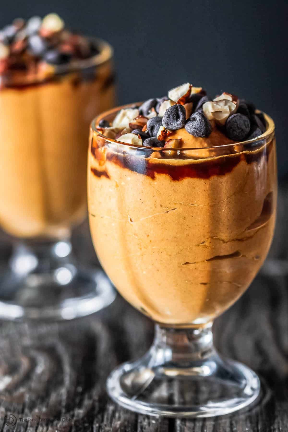 Scrumptious greek yogurt pumpkin parfait in two tall glasses.