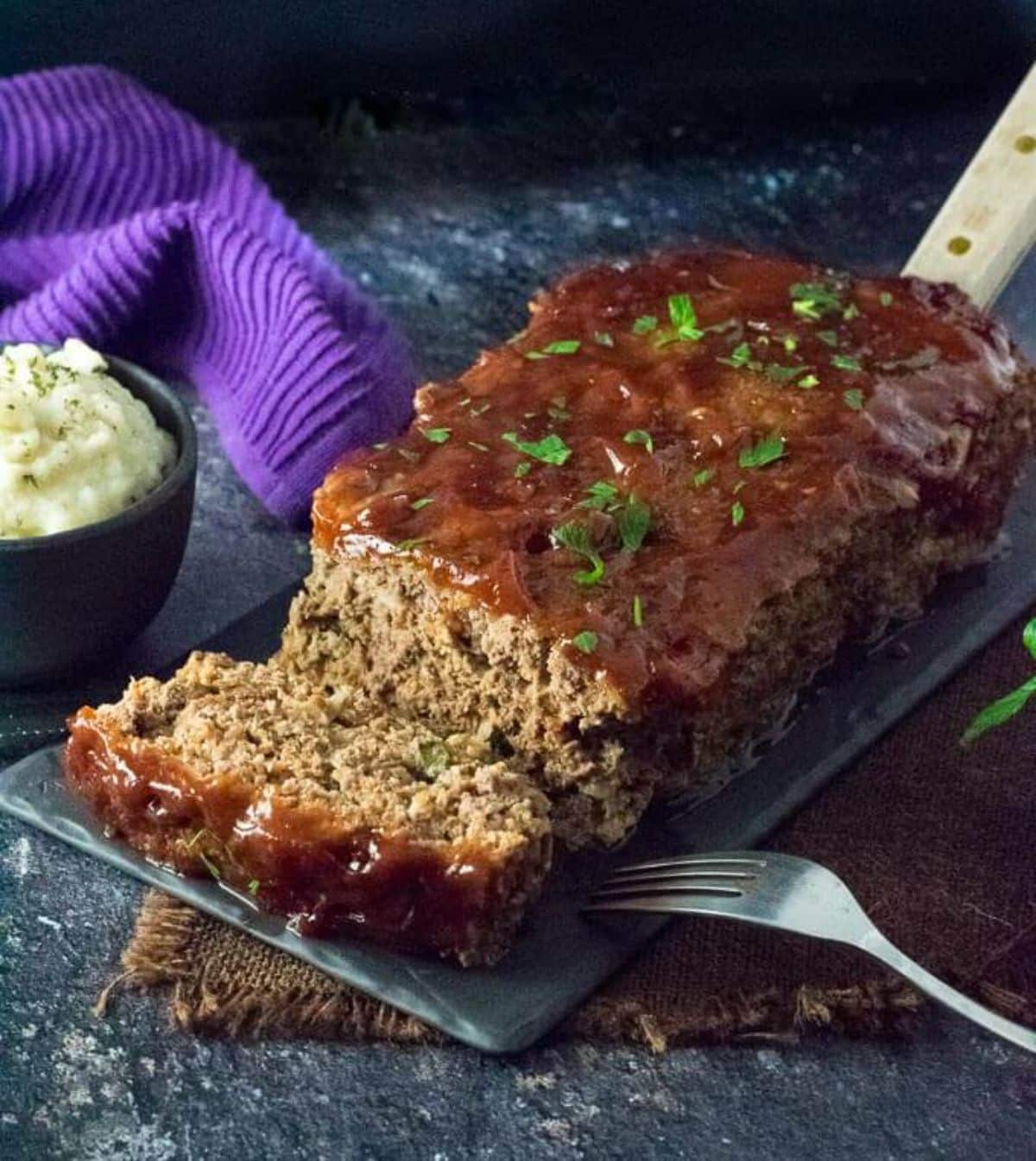 Mouth-watering venison meatloaf on a gray tray.