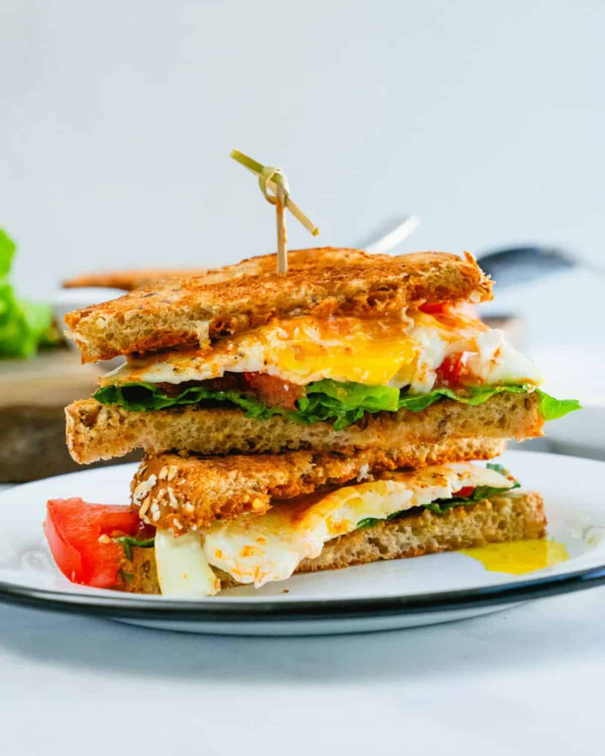 Sliced ultimate fried egg sandwich on a plate.