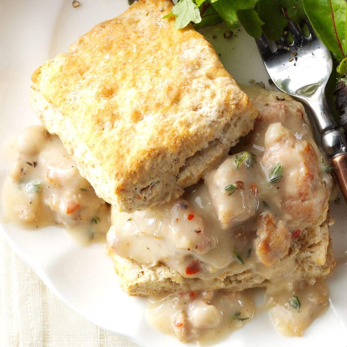 Juicy makeover biscuits and gravy with a piece of bread on a white plate with a fork.