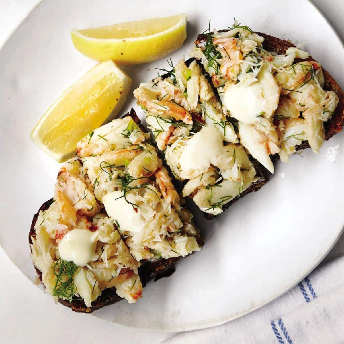 Delicious crab toast with lemon on a white plate.