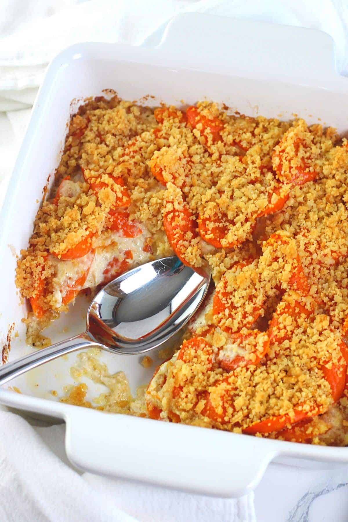 Crispy baked horseradish carrots in a white casserole with a spoon.