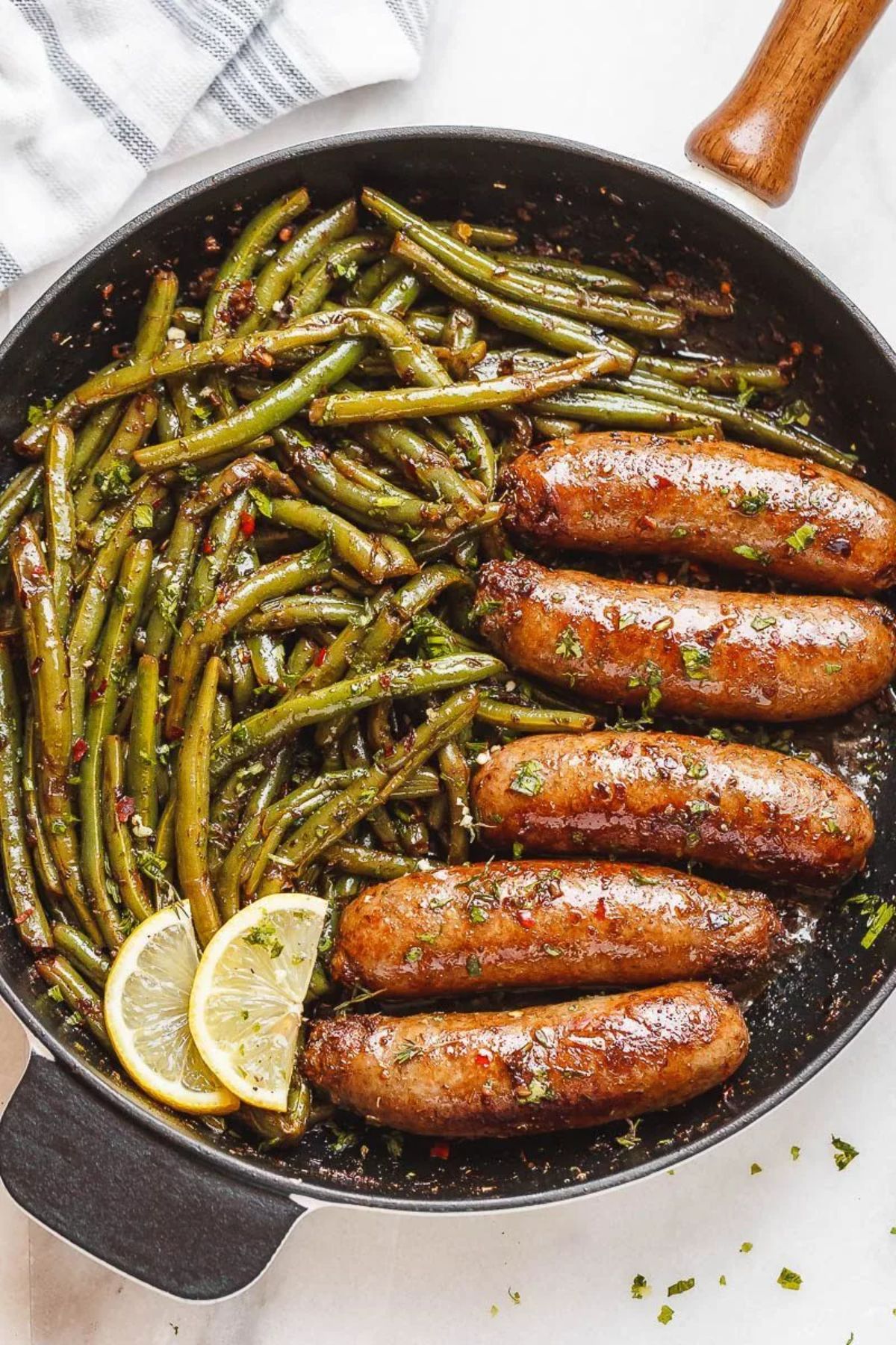 Mouth-watering garlic butter sausages with lemon green beans in a skillet.