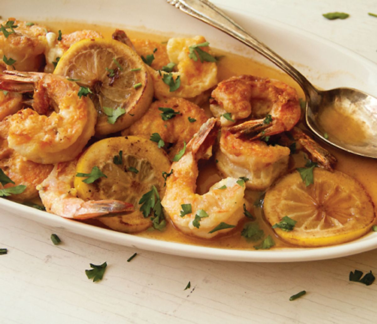 Juicy shrimp francese in a white bowl with a spoon.