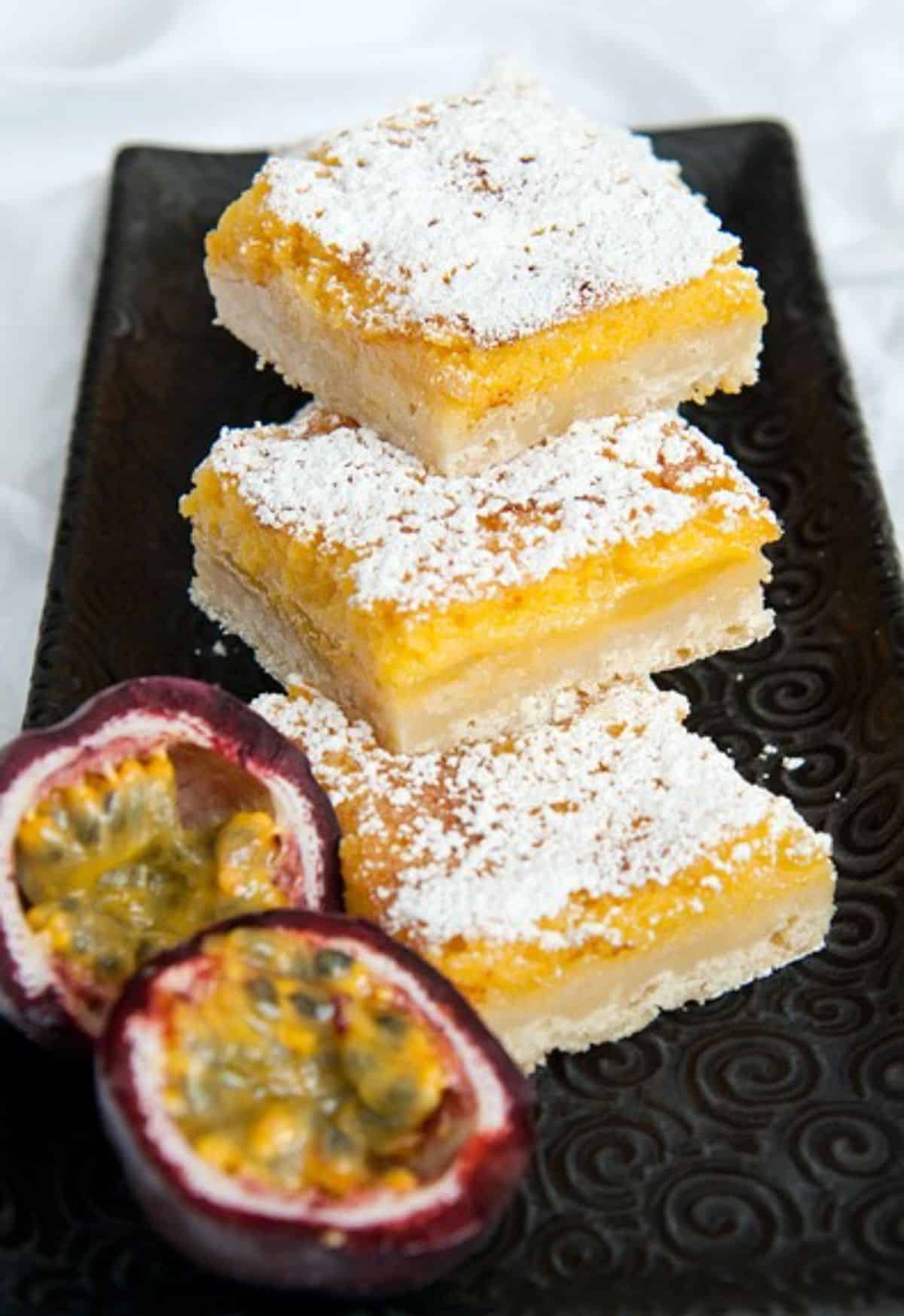 Delicious passion fruit bars on a black tray.