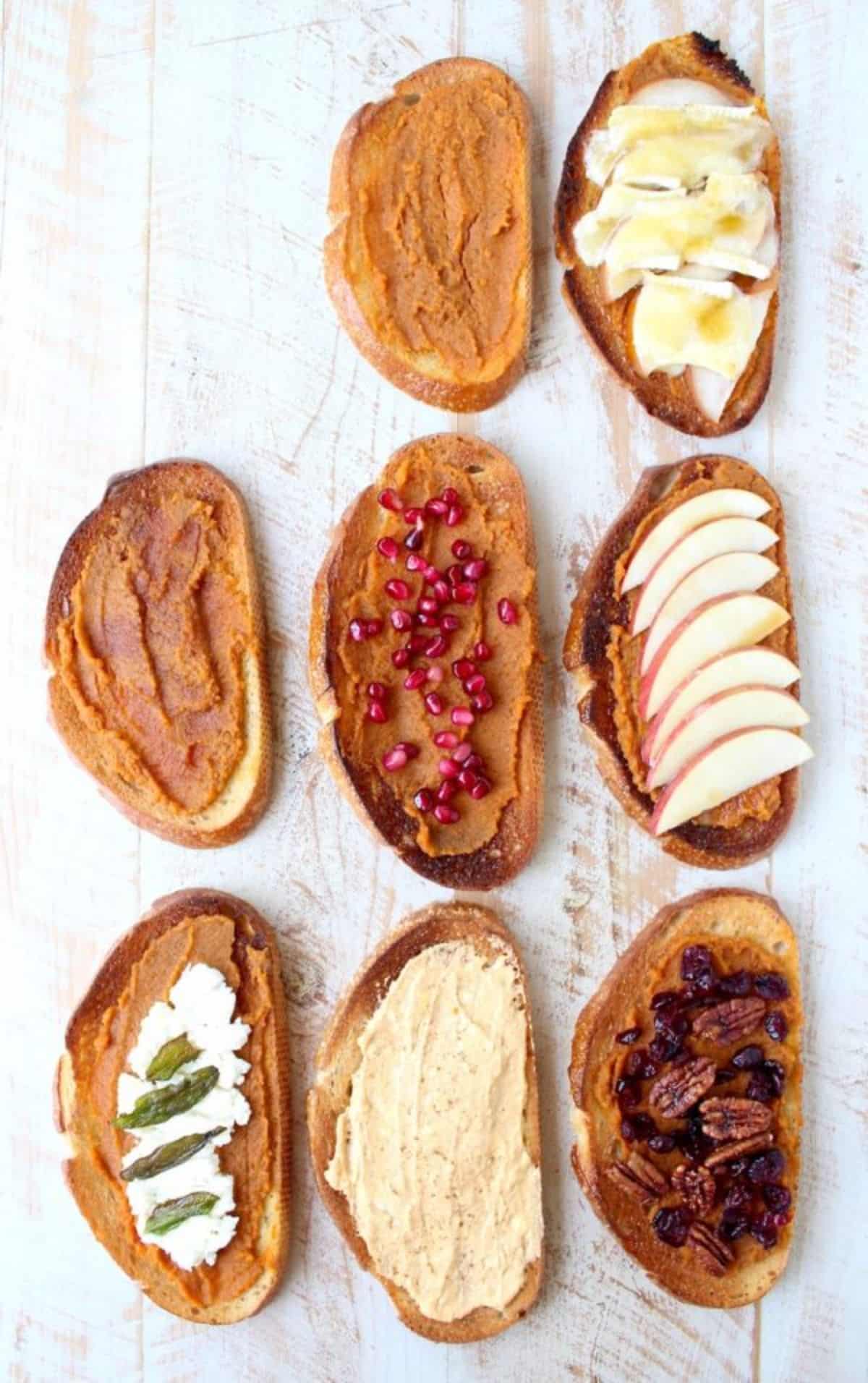 Healthy pumpkin toasts with different toppings on a wooden table.