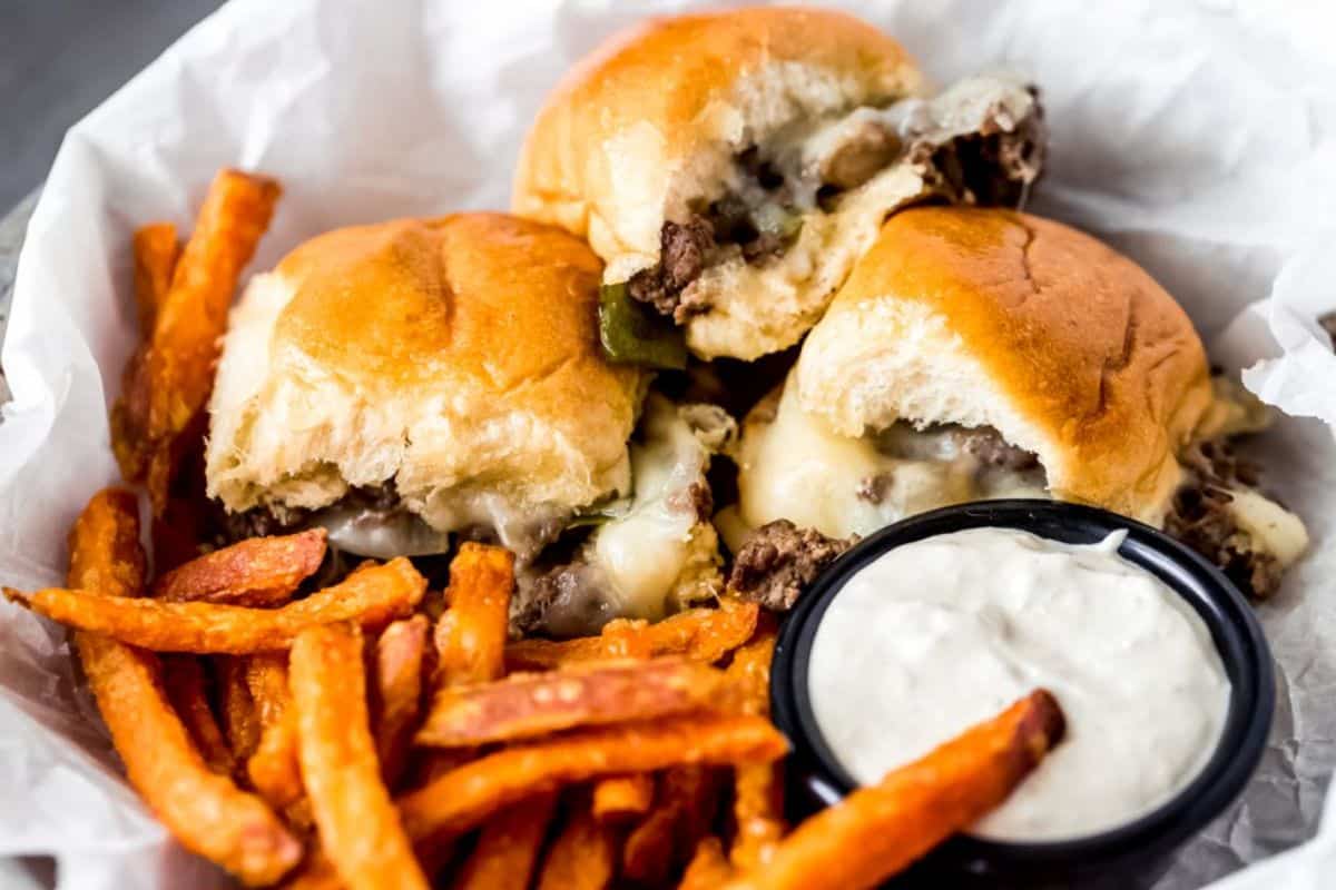 Delicious venison philly cheesesteak sliders with fries and a bowl of dip.