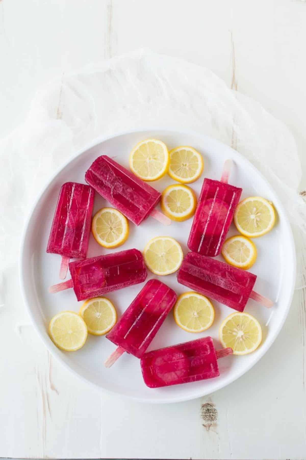 Fresh passion lemonade popsicles with lemon slices on a white tray.