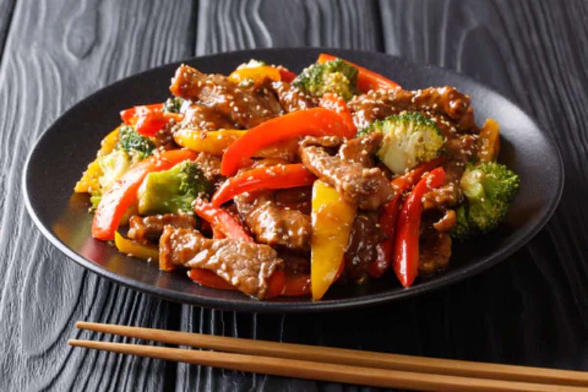 Healthy bison stir fry with vegetables on a black plate.