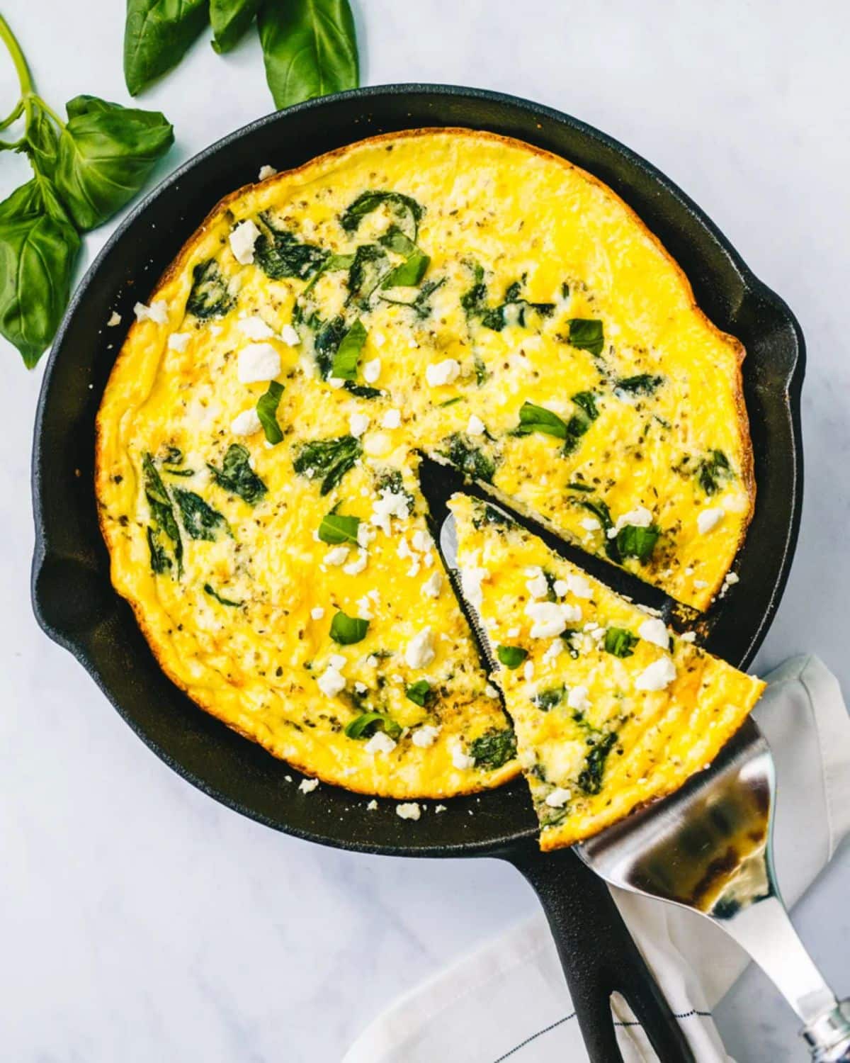 Flavorful easy frittata in a black skillet picked by a spatula.