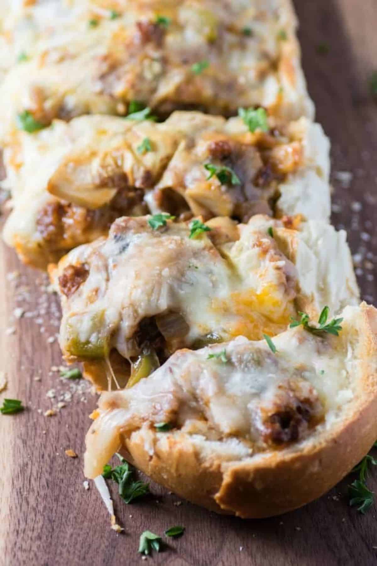 Sliced cheesy sausage stuffed bread on a wooden cutting board.