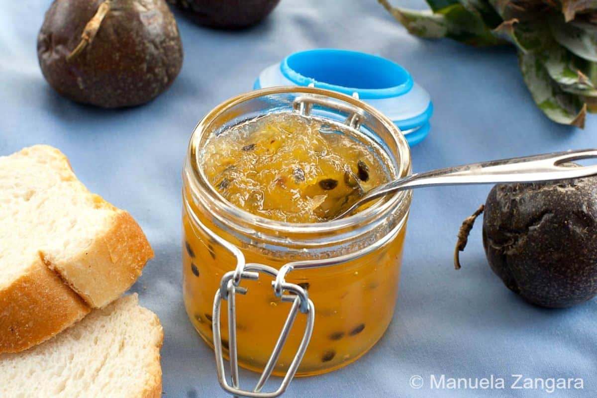 Fresh pineapple and passion fruit jam in a glass jar with a spoon.