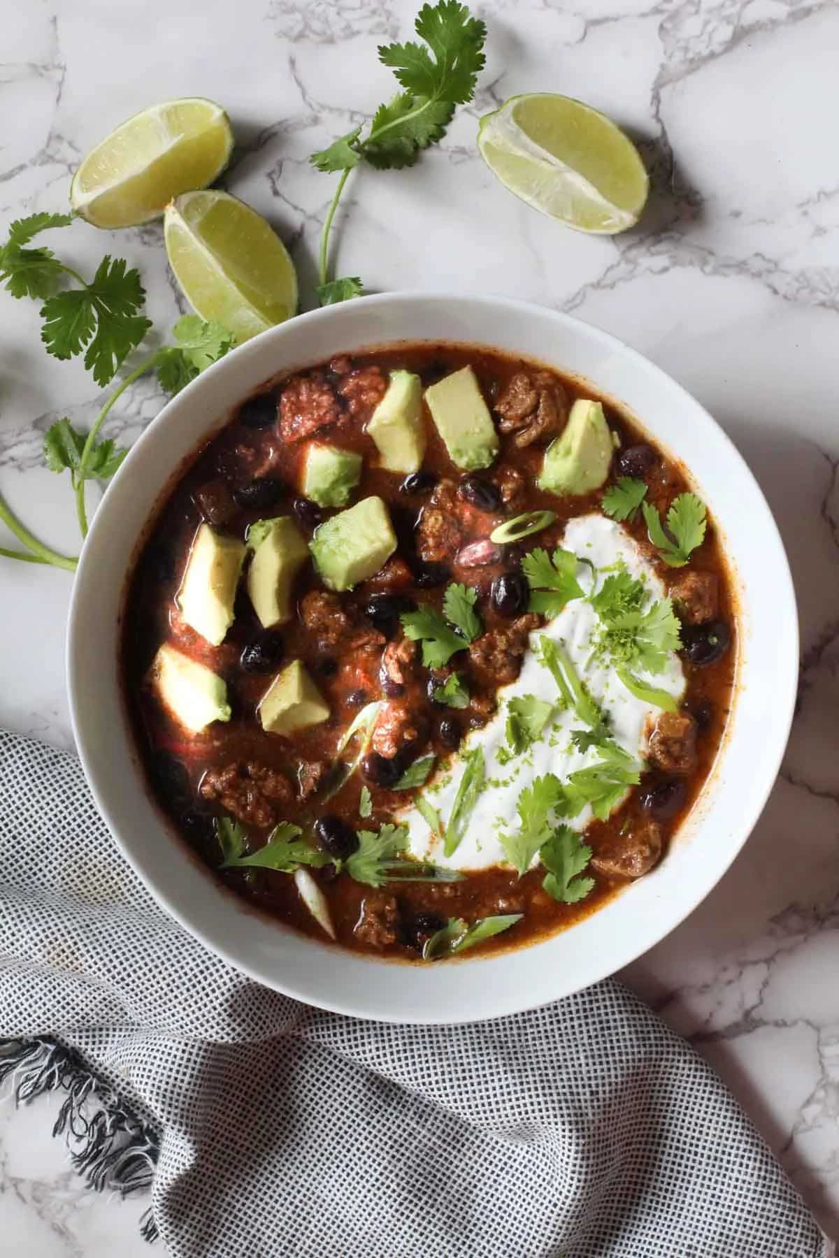 Healthy chipotle bison chili with lime crema in a white bowl.