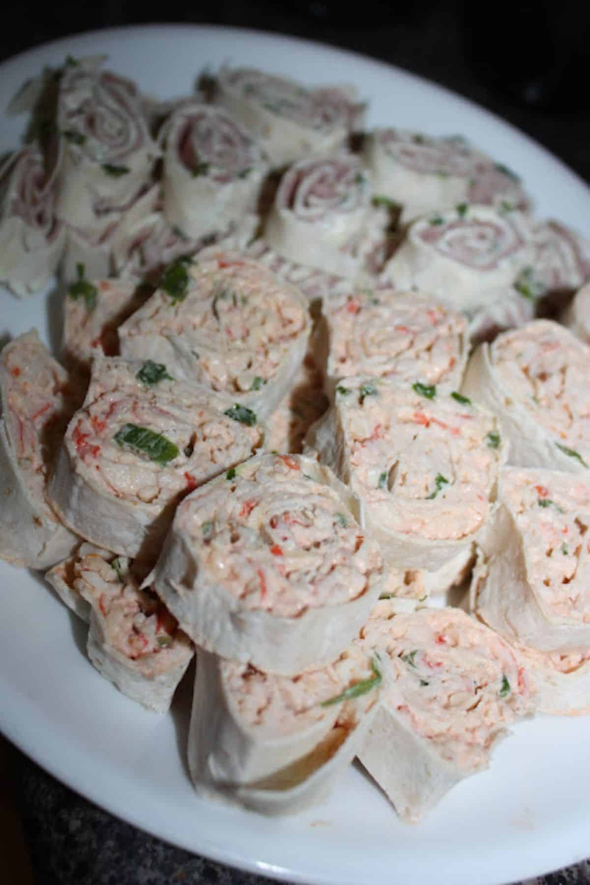 Tasty tortilla roll-ups on a white tray.