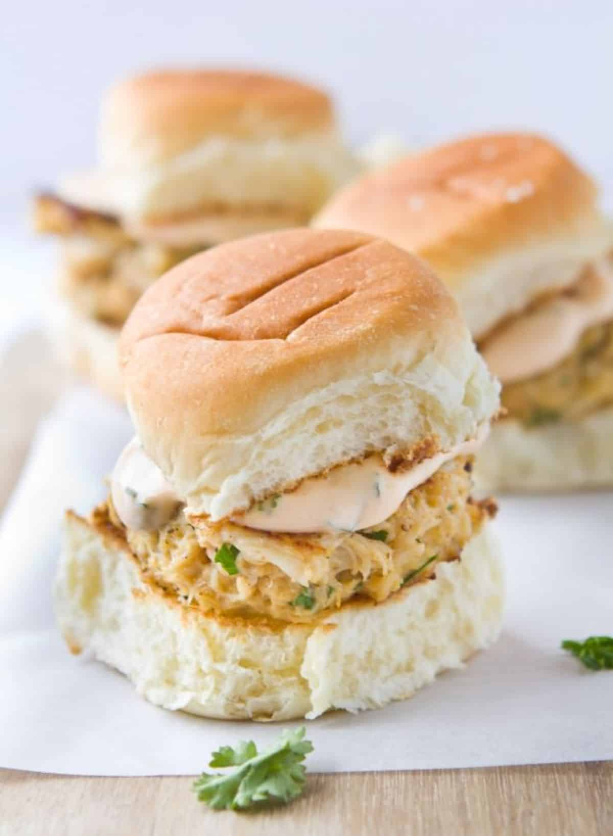 Delicious crab cake sliders on a wooden tray.