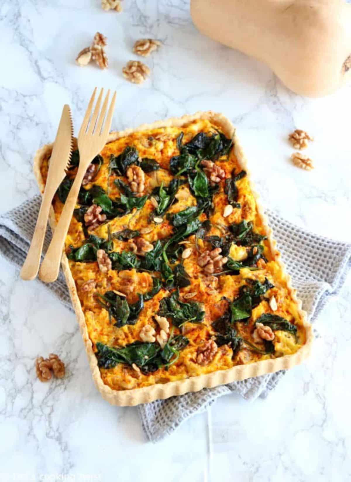 Mouth-watering pumpkin, spinach, and goat cheese quiche on a countertop.