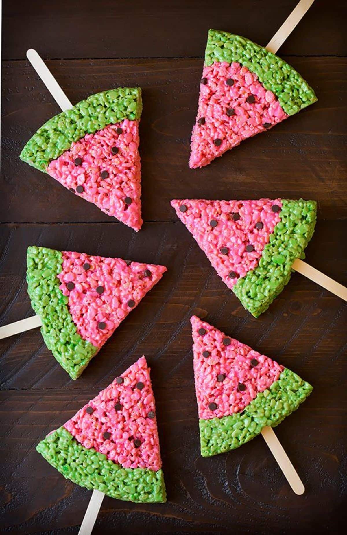 Crunchy watermelon rice krispy treat pops on a wooden table.