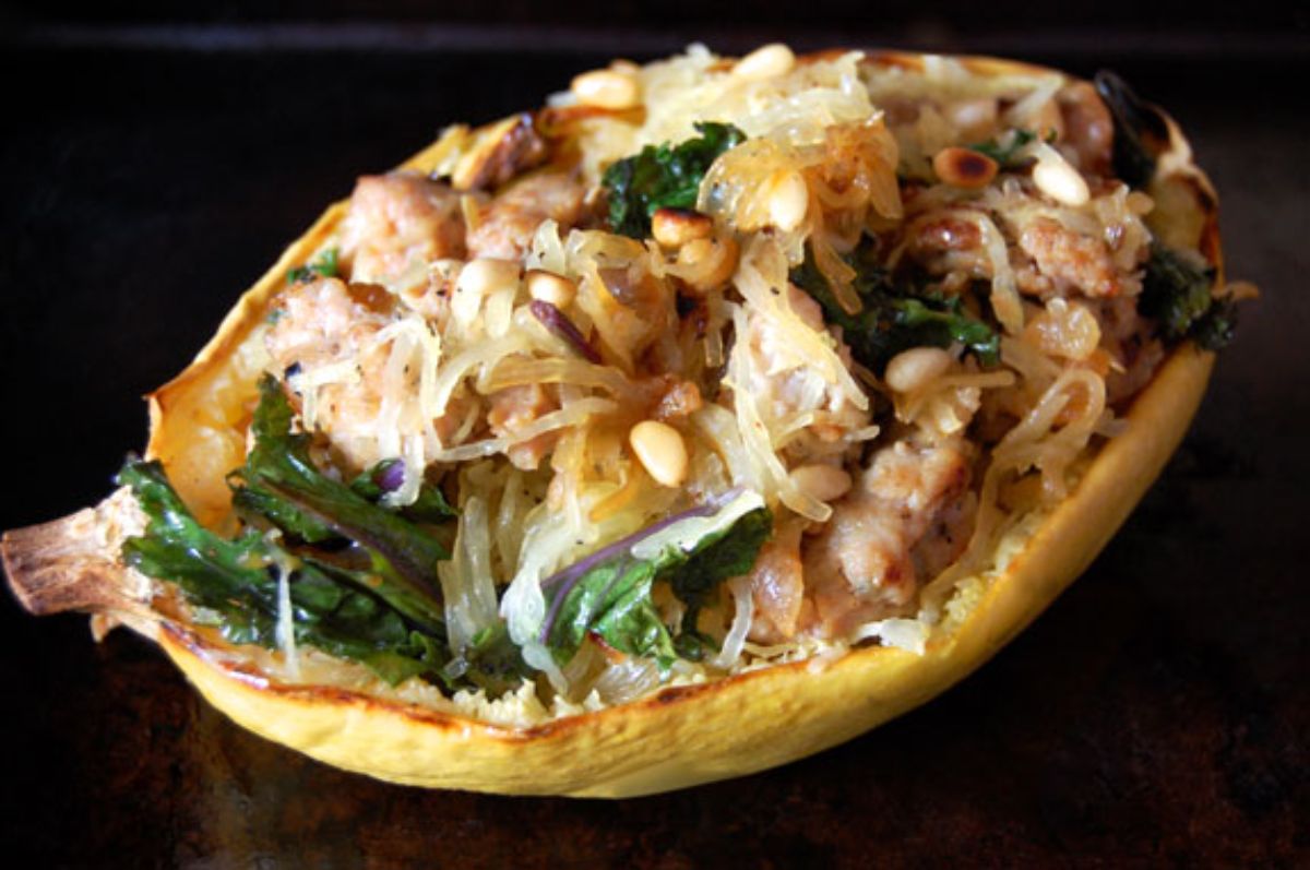 Healthy sausage, kale, and spaghetti squash boats on a black background.