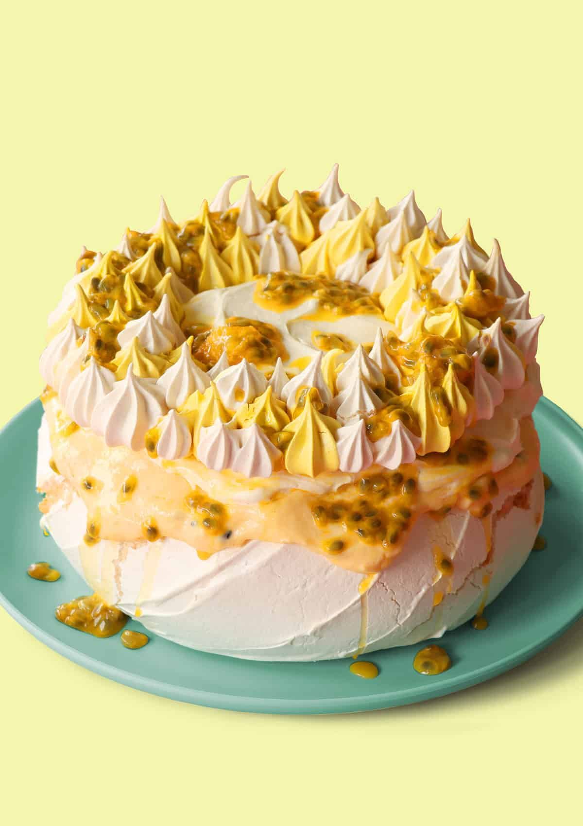 Mouth-watering passionfruit pavlova cake on a green tray.