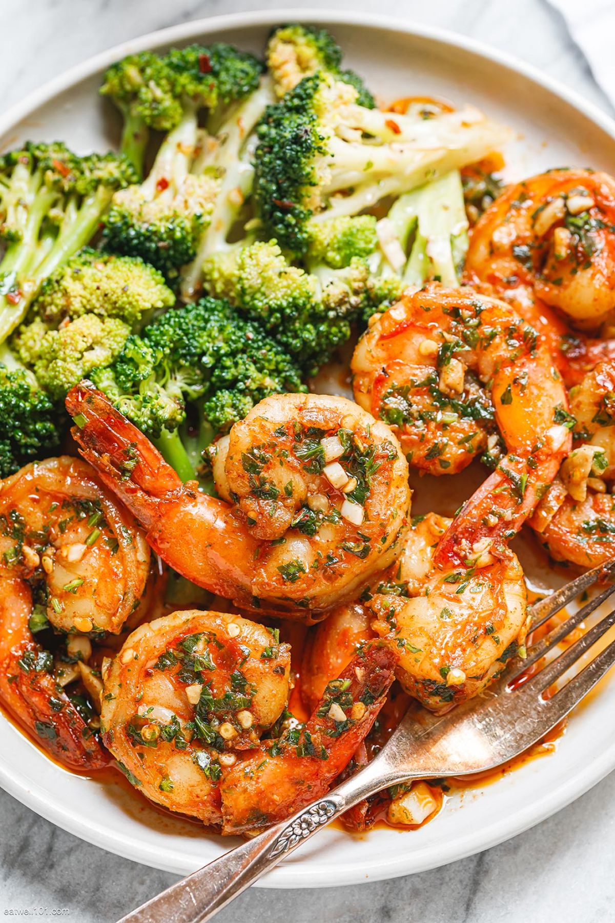 Scrumptious garlic butter shrimp and broccoli on a white plate with a fork.