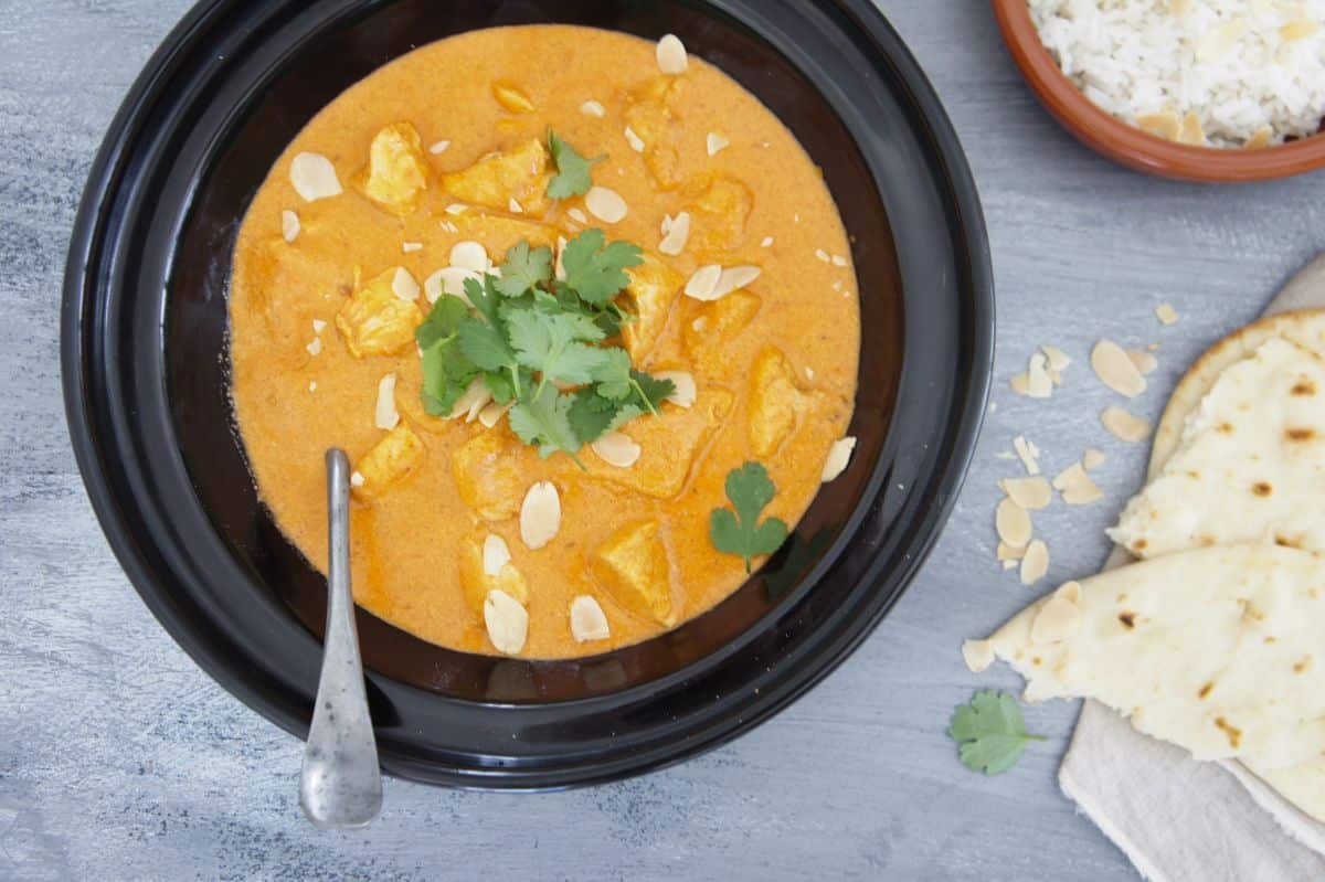 Creamy butter chicken in a black bowl.