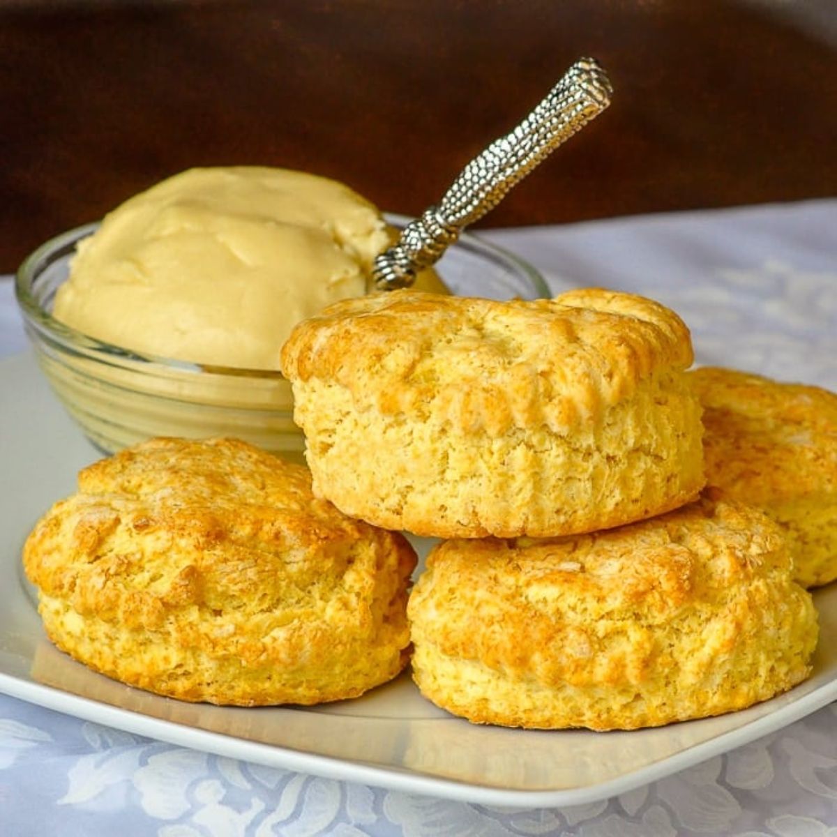 Flavorful maple butter biscuits with a bowl of butter on a white tray.