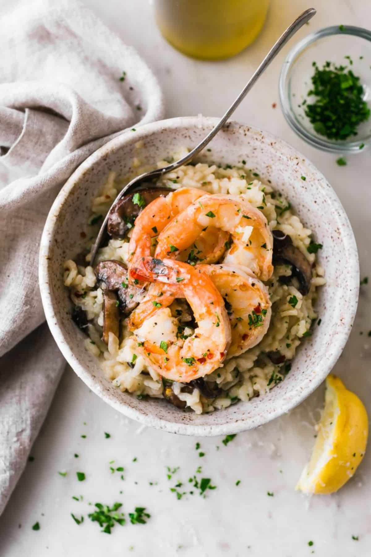 Flavorful mushroom parmesan shrimp risotto in a bowl with a spoon.
