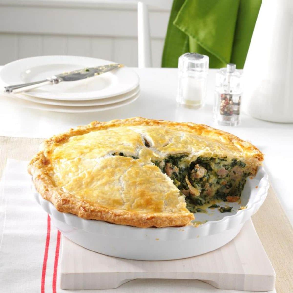 Tasty italian sausage and spinach pie in a white casserole.