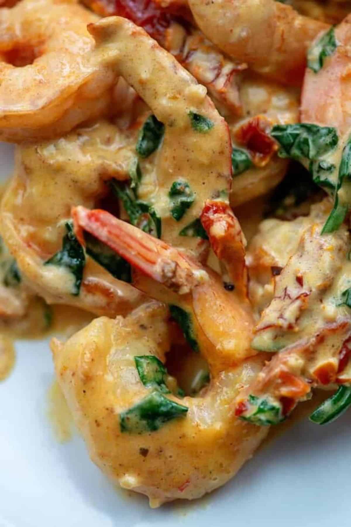 Creamy tuscan shrimp on a white plate.