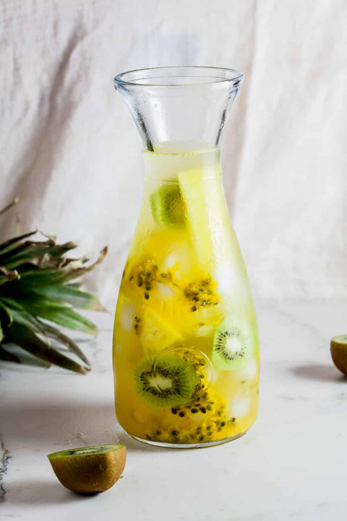 Refreshing pineapple, kiwi, and passion fruit flavored water in a glass jar.