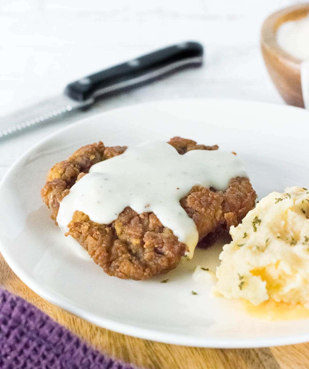 Flavorful chicken fried venison with mashed potatoes on a white plate.