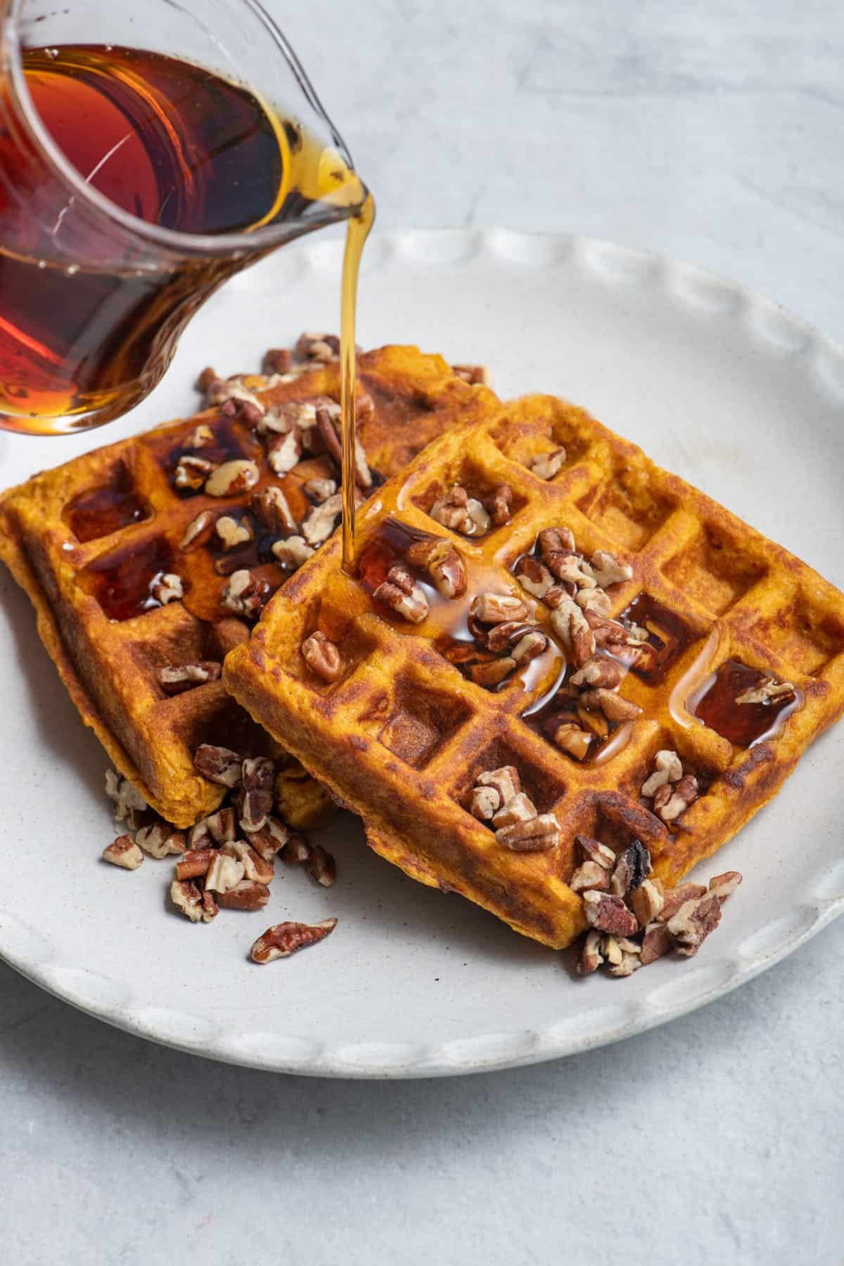 Mouth-watering sweet potato waffles drizzled with syrup on a white plate.