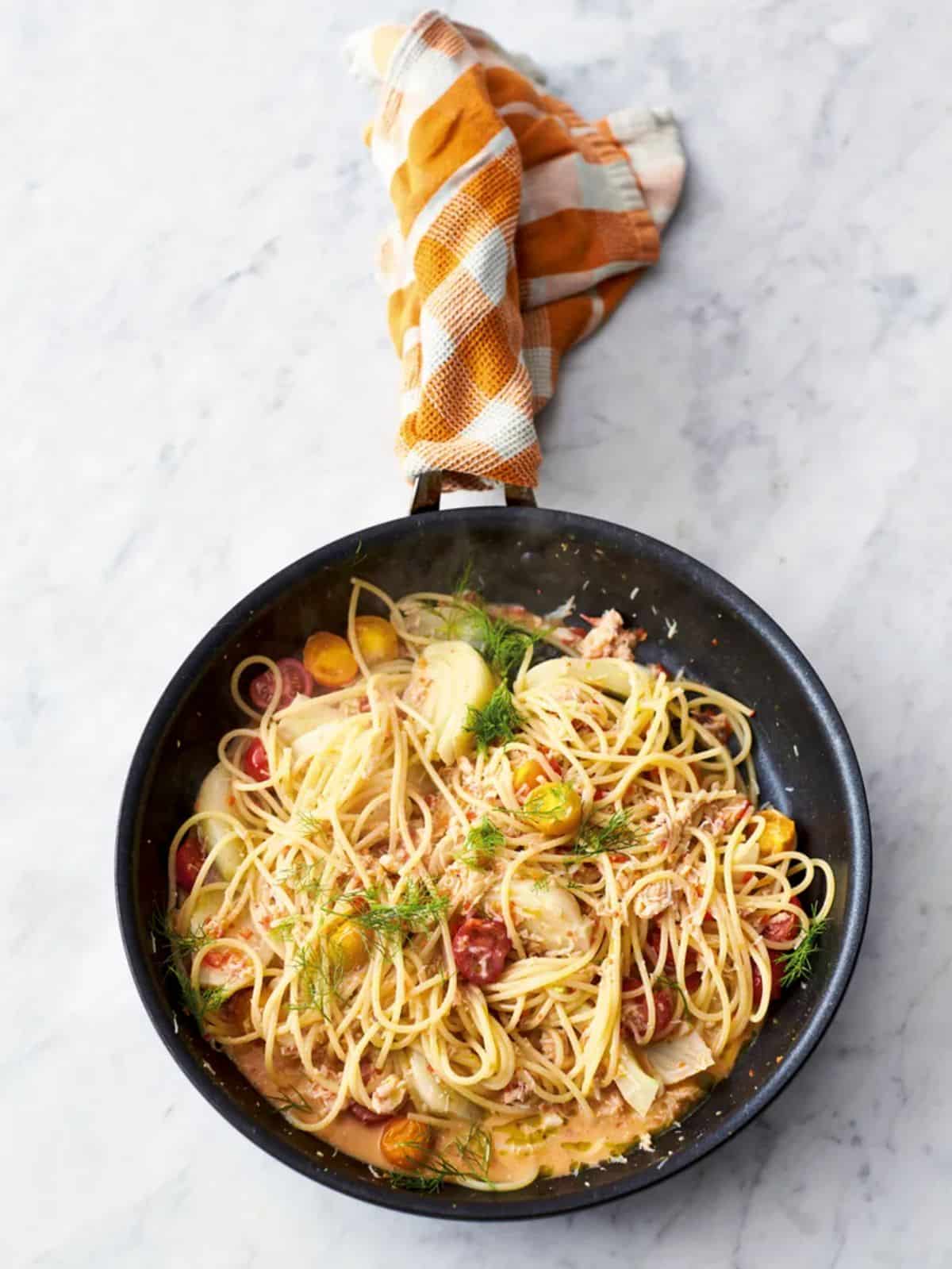 Healthy crab and fennel spaghetti in a black skillet.