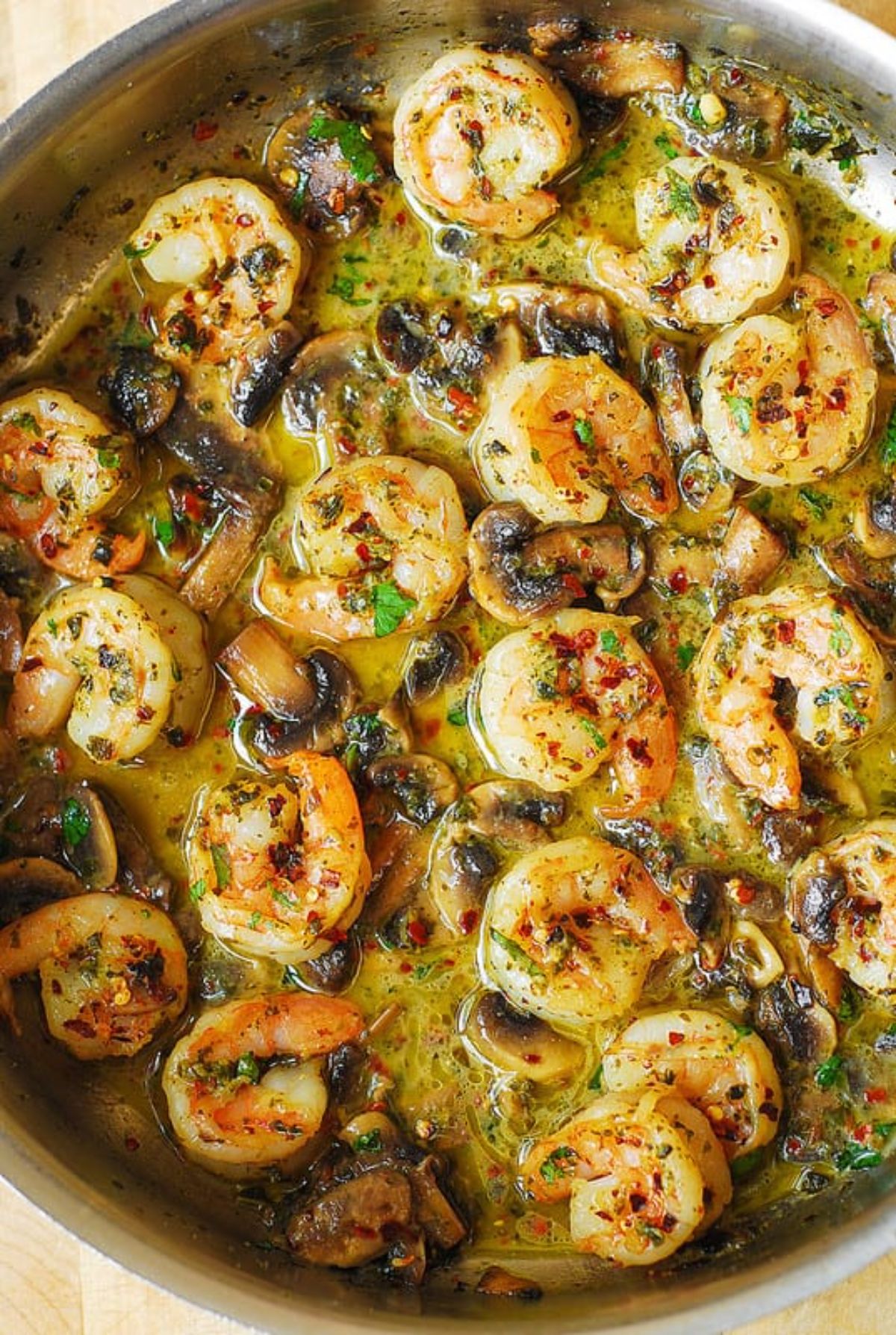 Juicy pesto shrimp with mushroomsin a skillet.