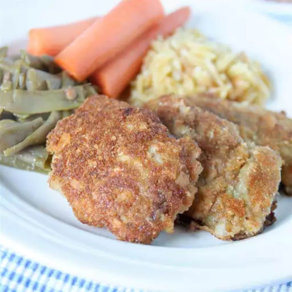 Tasteful venison schnitzel with veggies on a white plate.