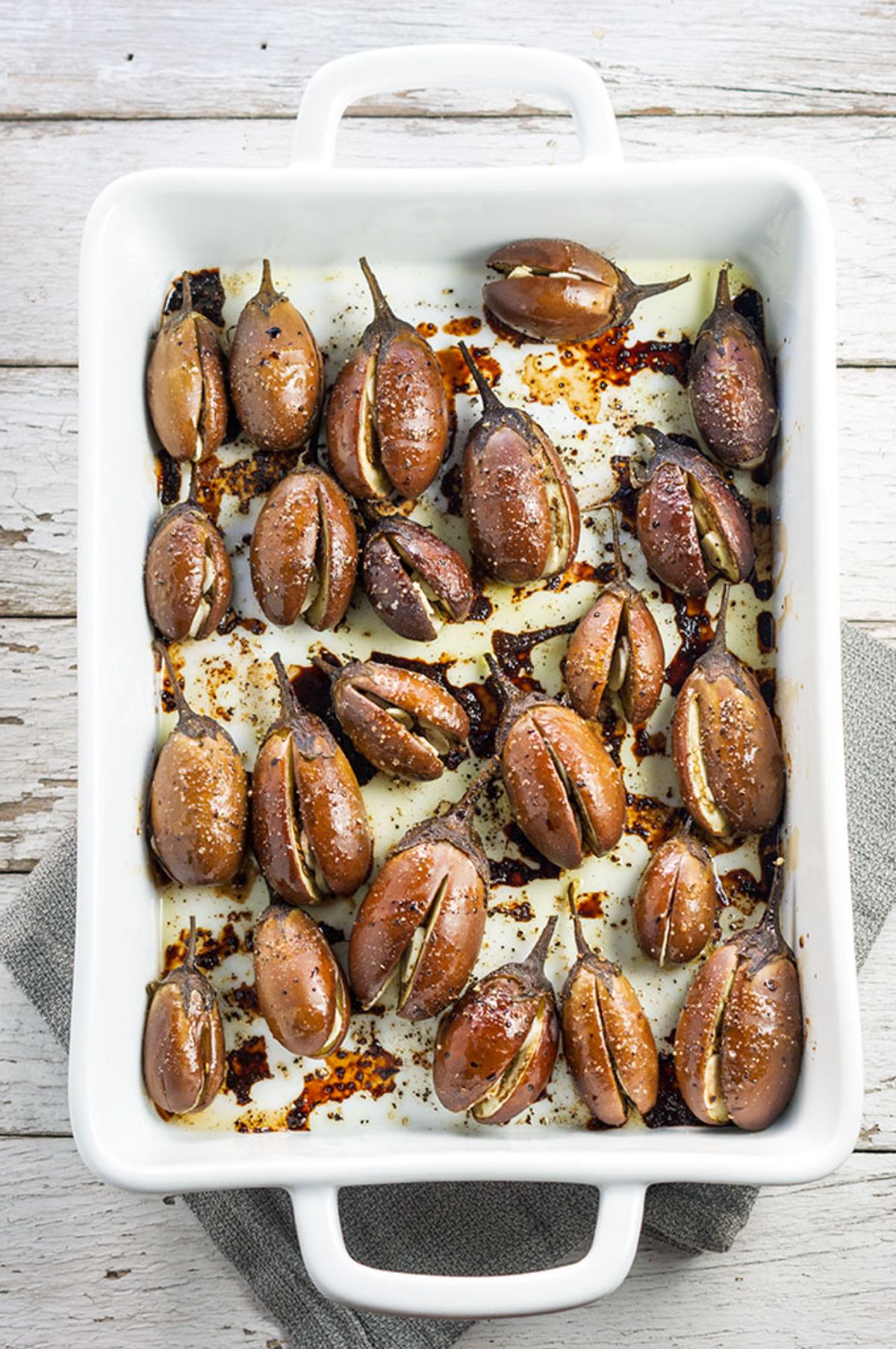 Scrumptious roasted mini eggplants in a white casserole.