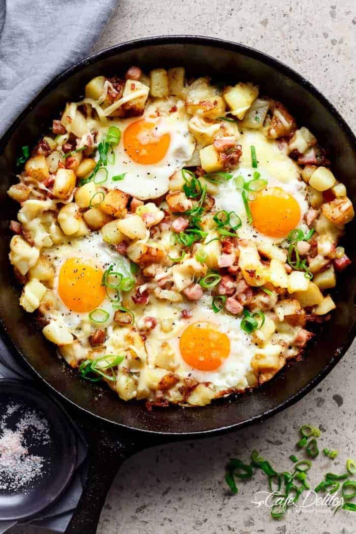 Mouth-watering cheesy bacon and egg hash in a black skillet.