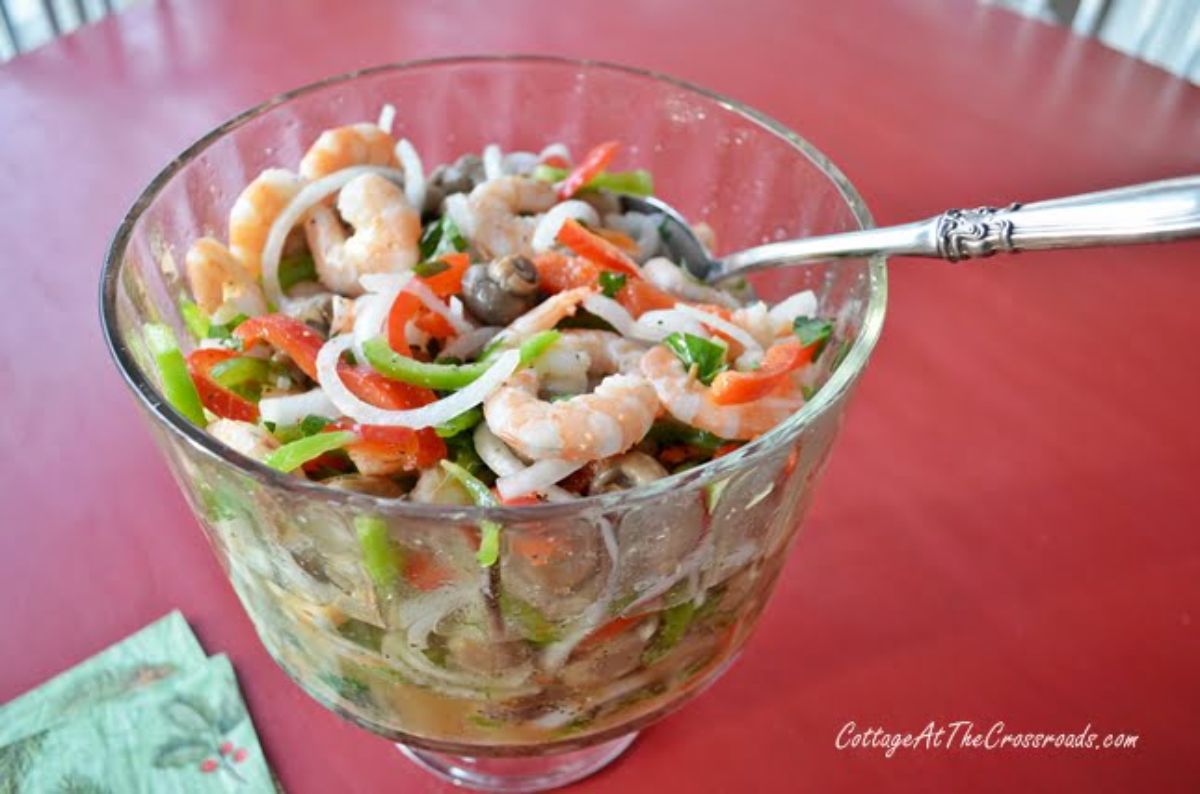 Tasty marinated shrimp in glass bowl with a spoon.