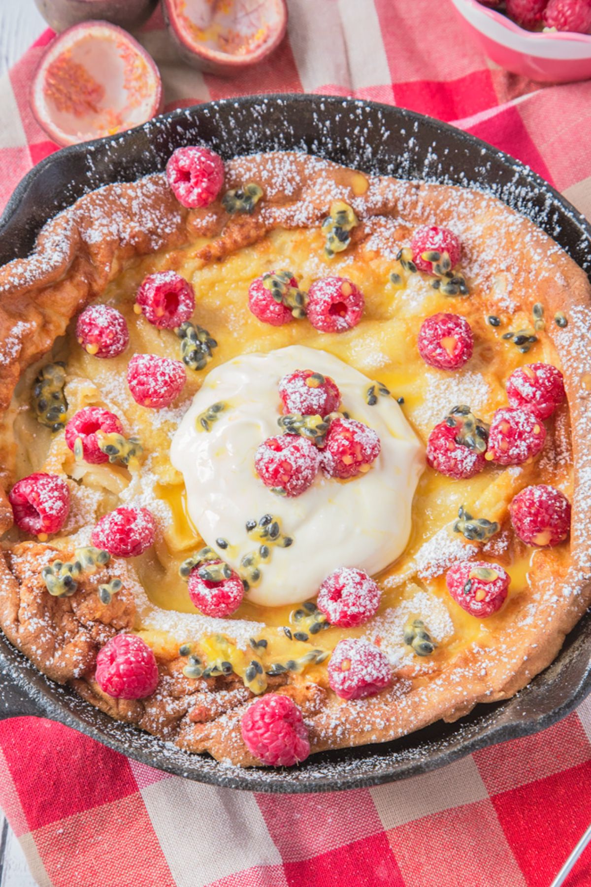 Scrumptious passion fruit and raspberry pancake in a black skillet.