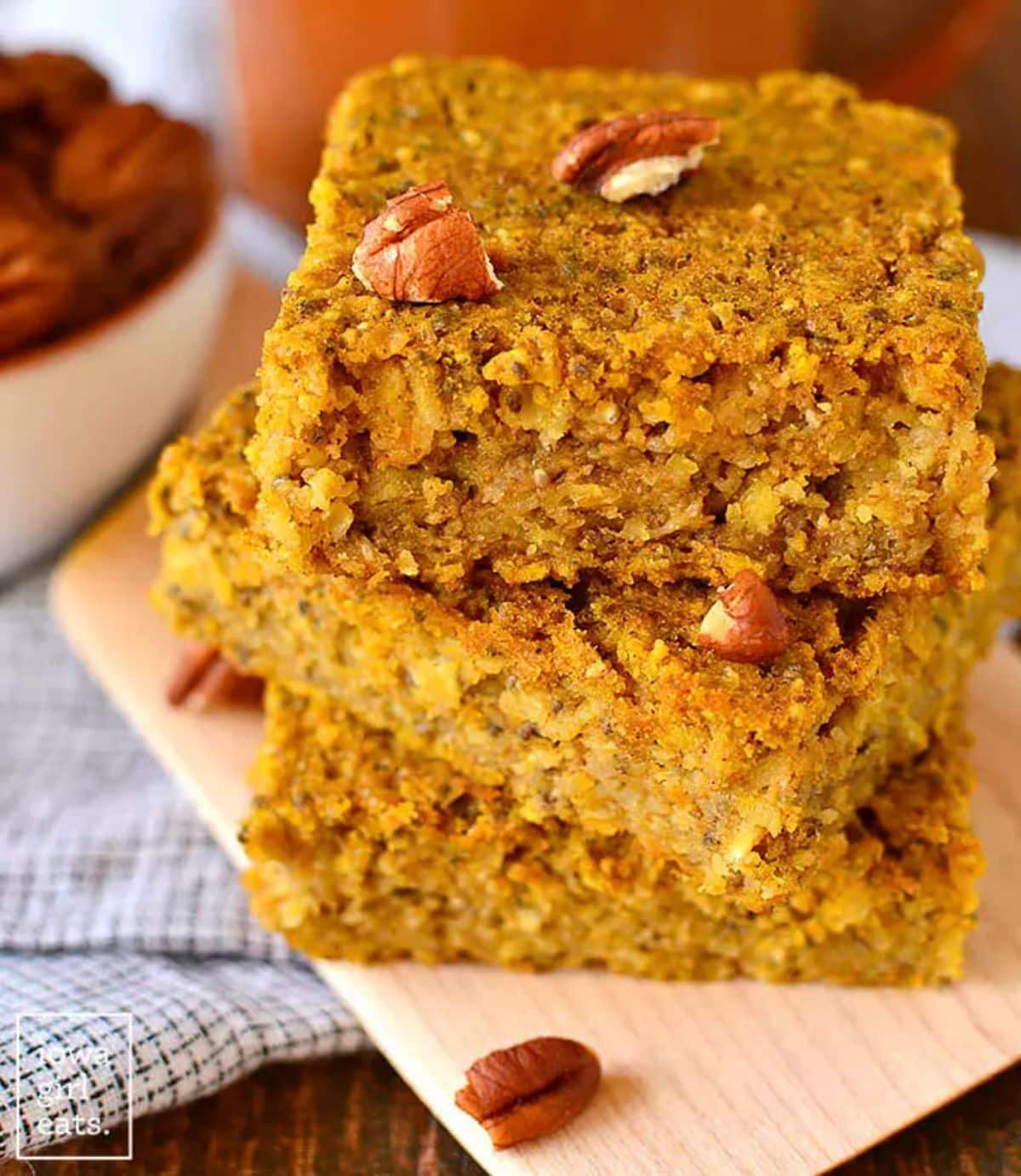 A pile of maple pumpkin oatmeal breakfast bars on a wooden cutting board.