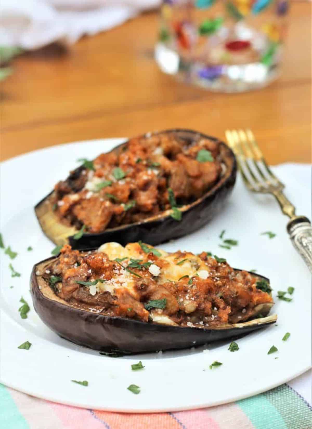Mouth-watering stuffed baby eggplant on a white plate with a fork.