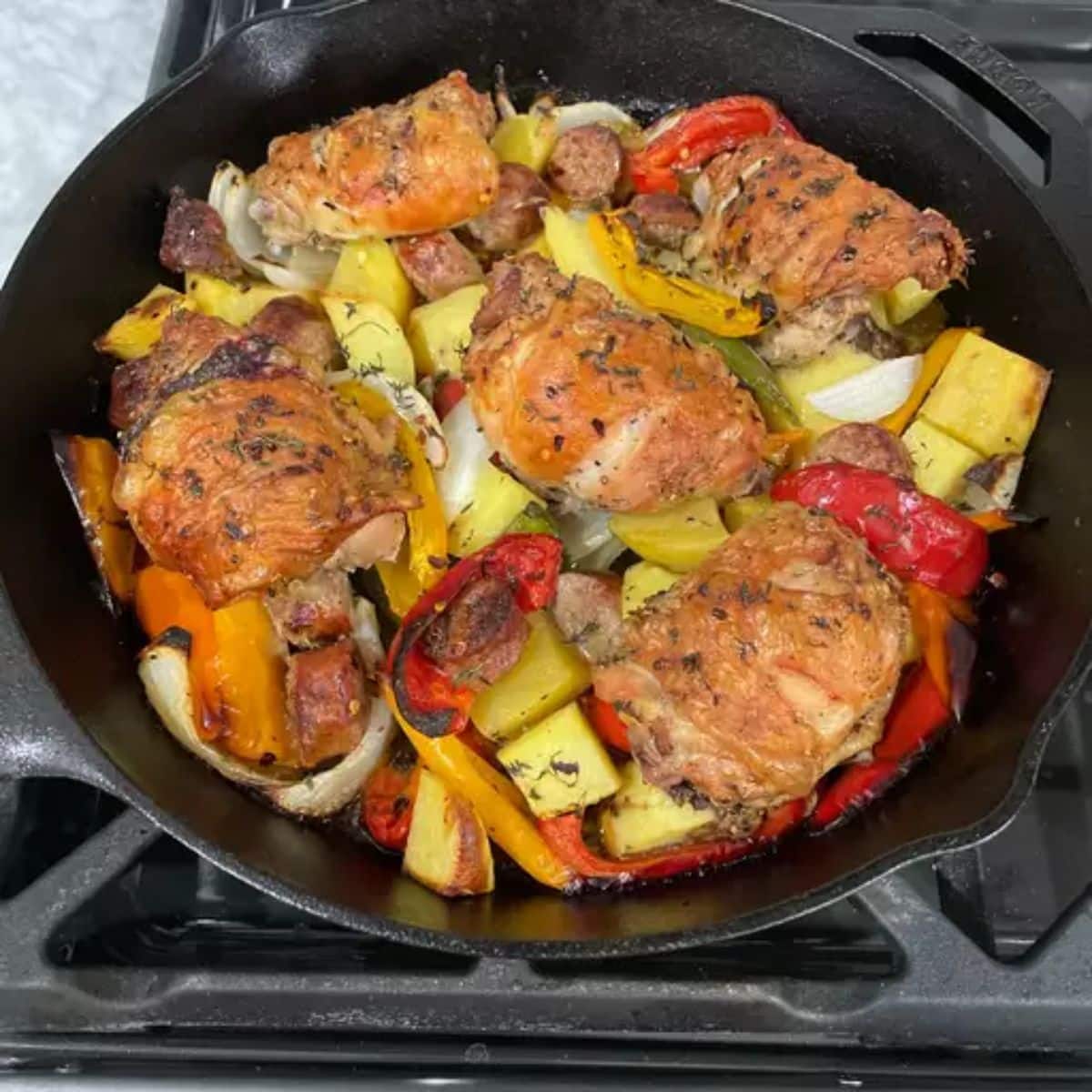 Delicious chicken, sausage, peppers, and potatoes in a black skillet.