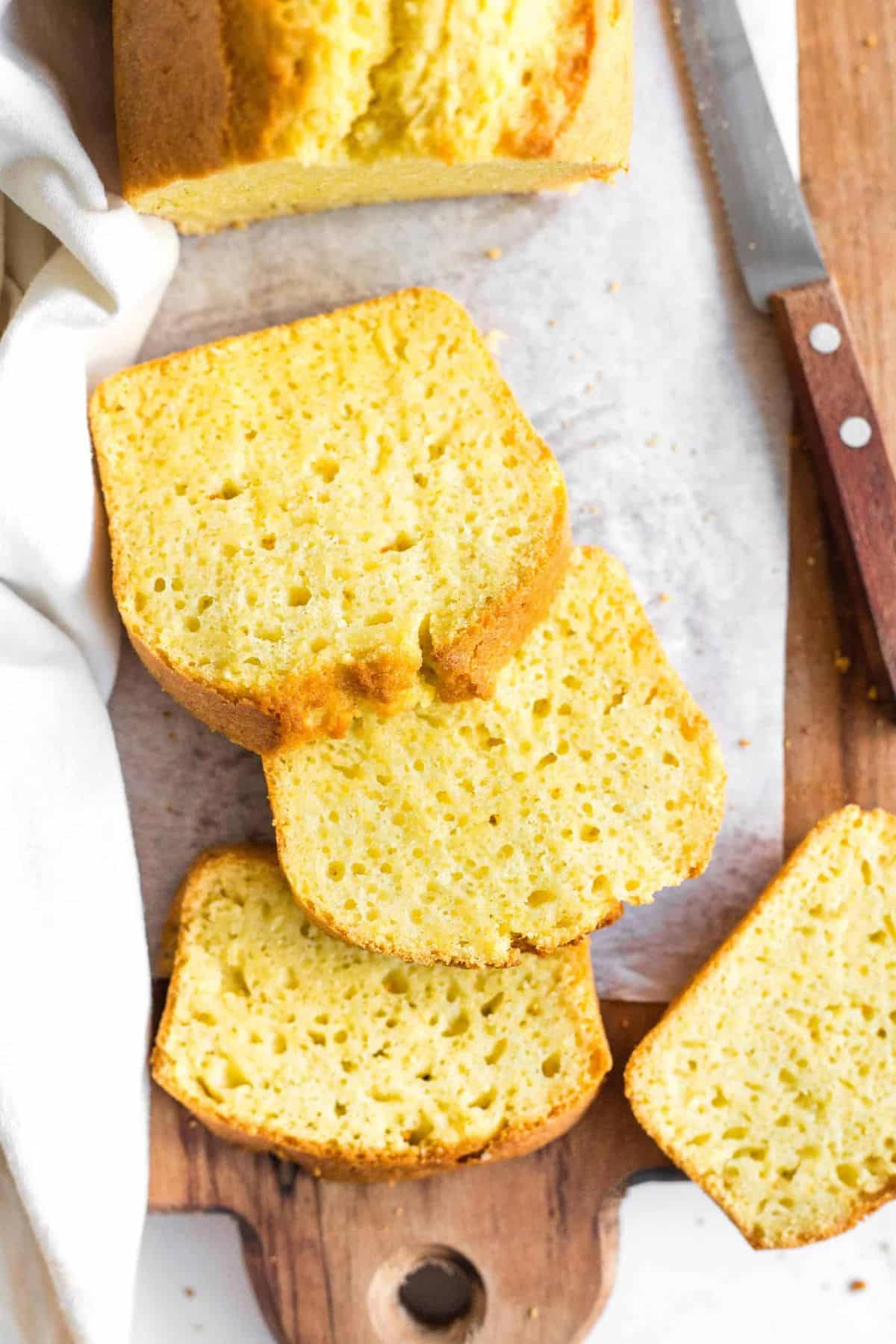 Partially sliced corn flour bread on a wooden cutting board.