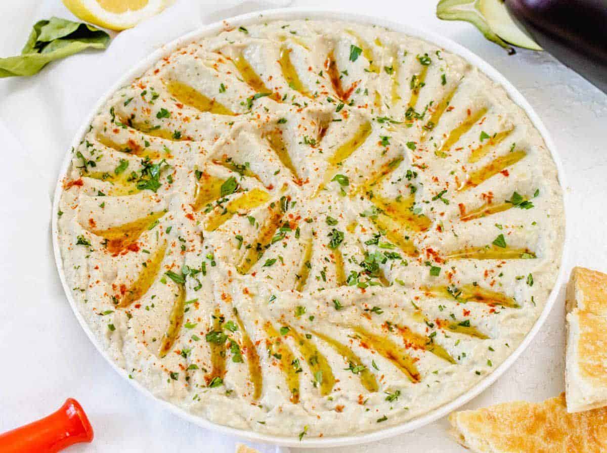 Juicy eggplant dip - baba ganoush in a white bowl.