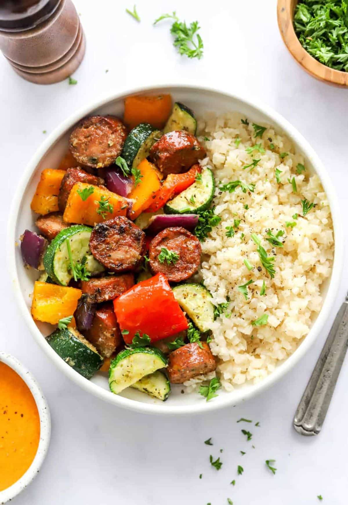 Healthy air fryer chicken sausage and veggies in a white bowl.
