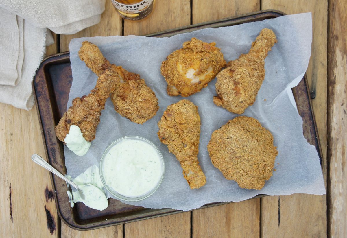 Crispy fried chicken with a bowl of dip on a baking tray.