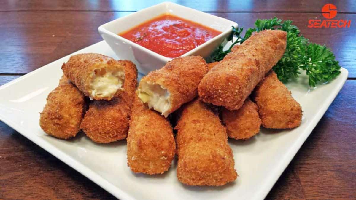 Crispy crab cheese sticks with a bowl of dip on a white tray.