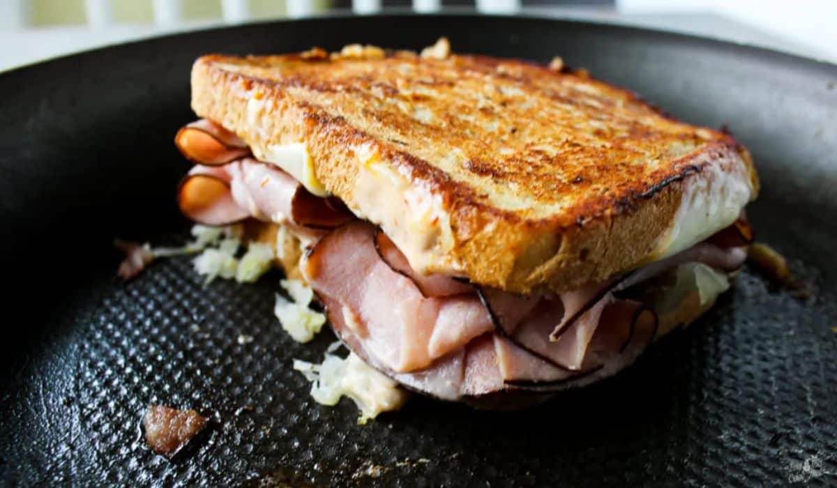Scrumptious ham reuben sandwich in a black pan.