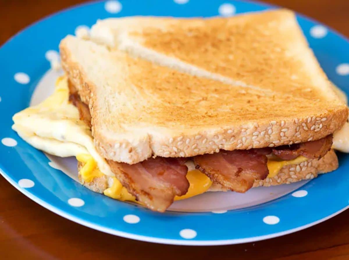 Tasty bacon, egg, and cheese sandwich on a blue plate.