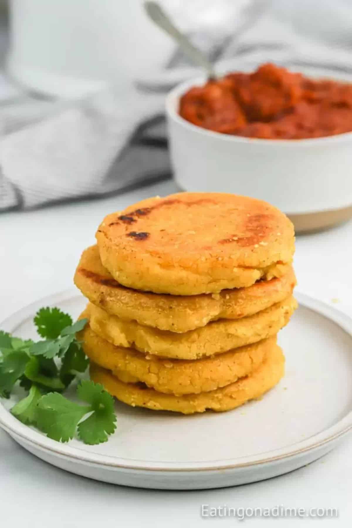 A pile of arepas on a white tray.